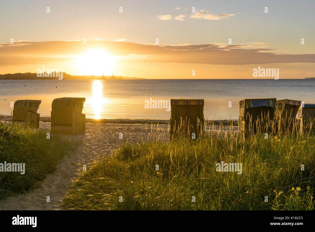 European Beach wicker chairs are placed decoratively on the beach for summer guests in the sunrise by the quiet sea Stock Photo