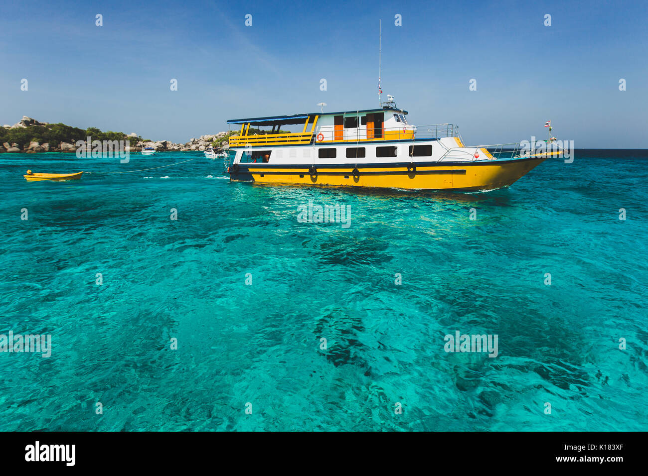 Tourist diving boat near island shore with turquoise clear transparent water. Idyllic view of Similan Islands Stock Photo