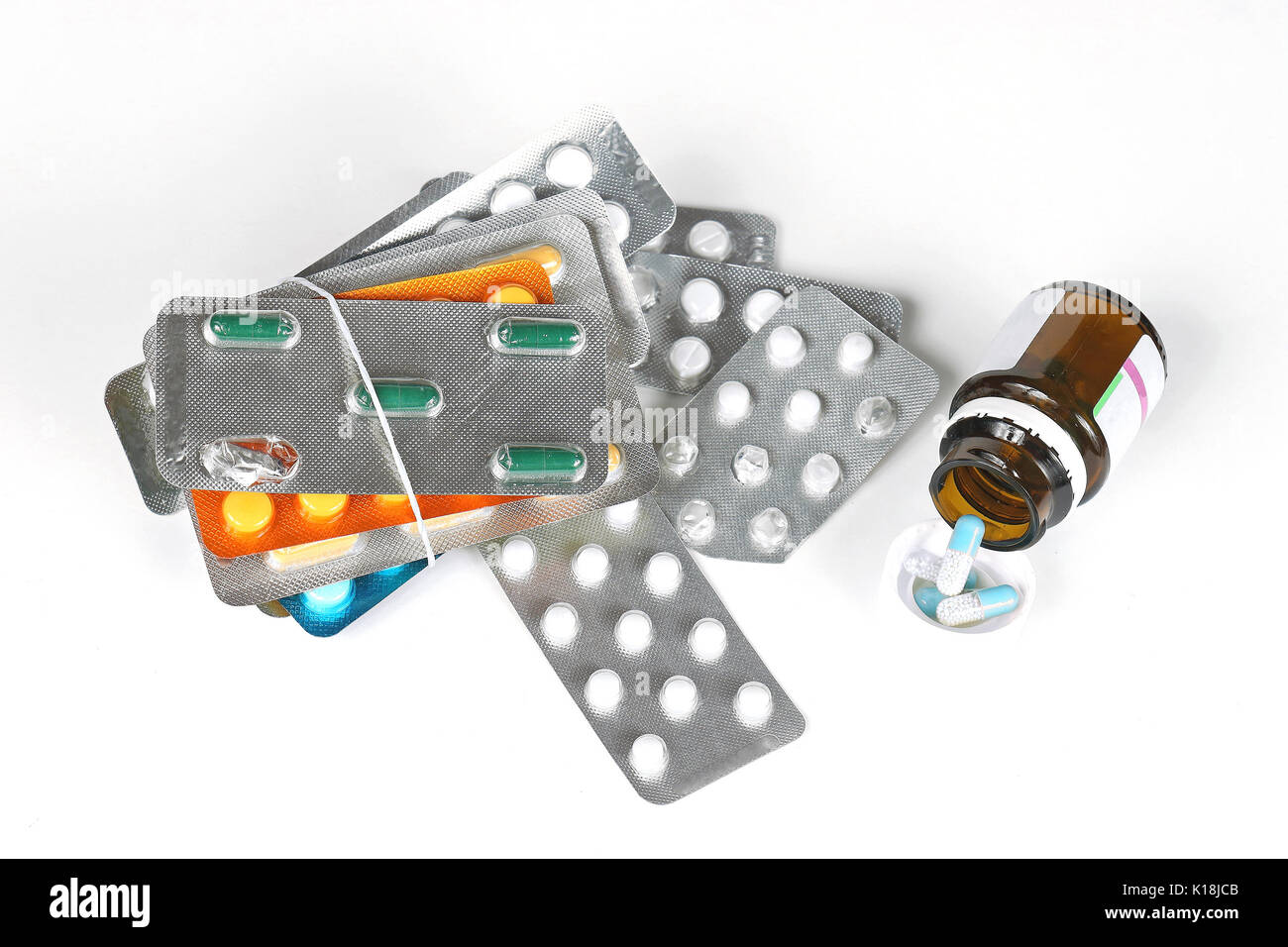 Open glass medicine container with pile of pills blisters Stock Photo