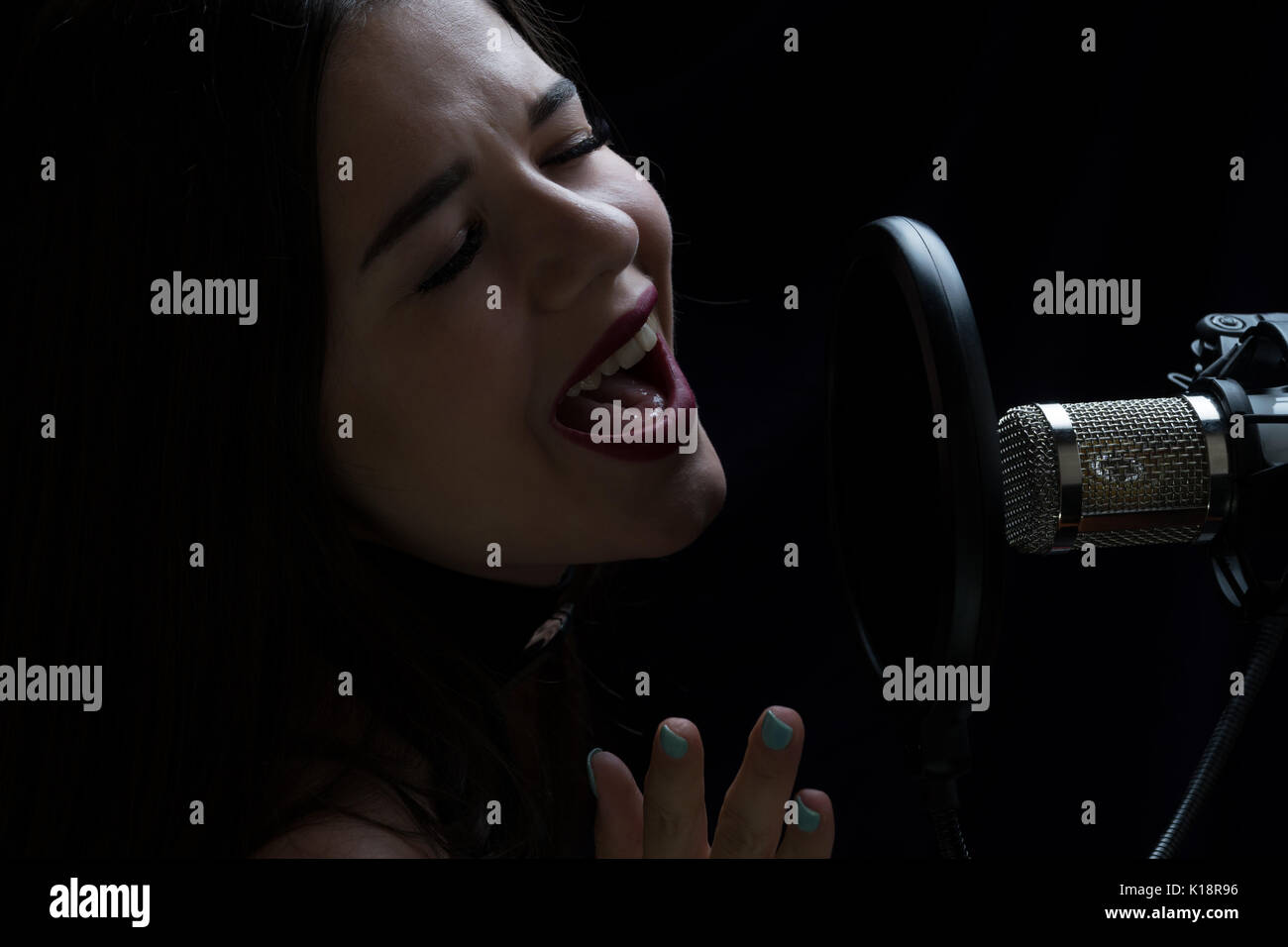Beautiful girl singing In Recording Studio with microphone Stock Photo