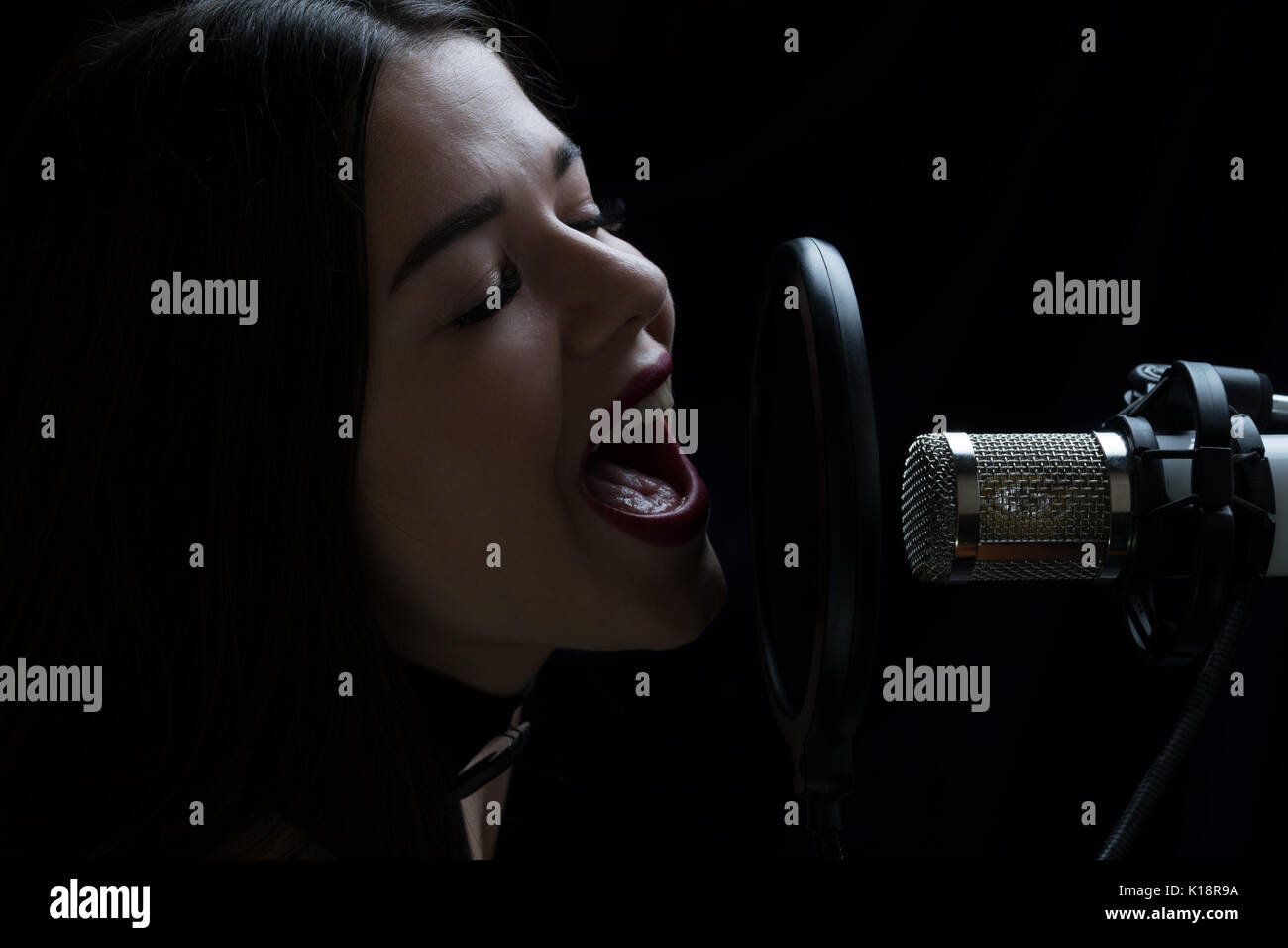 Beautiful girl singing In Recording Studio with microphone Stock Photo