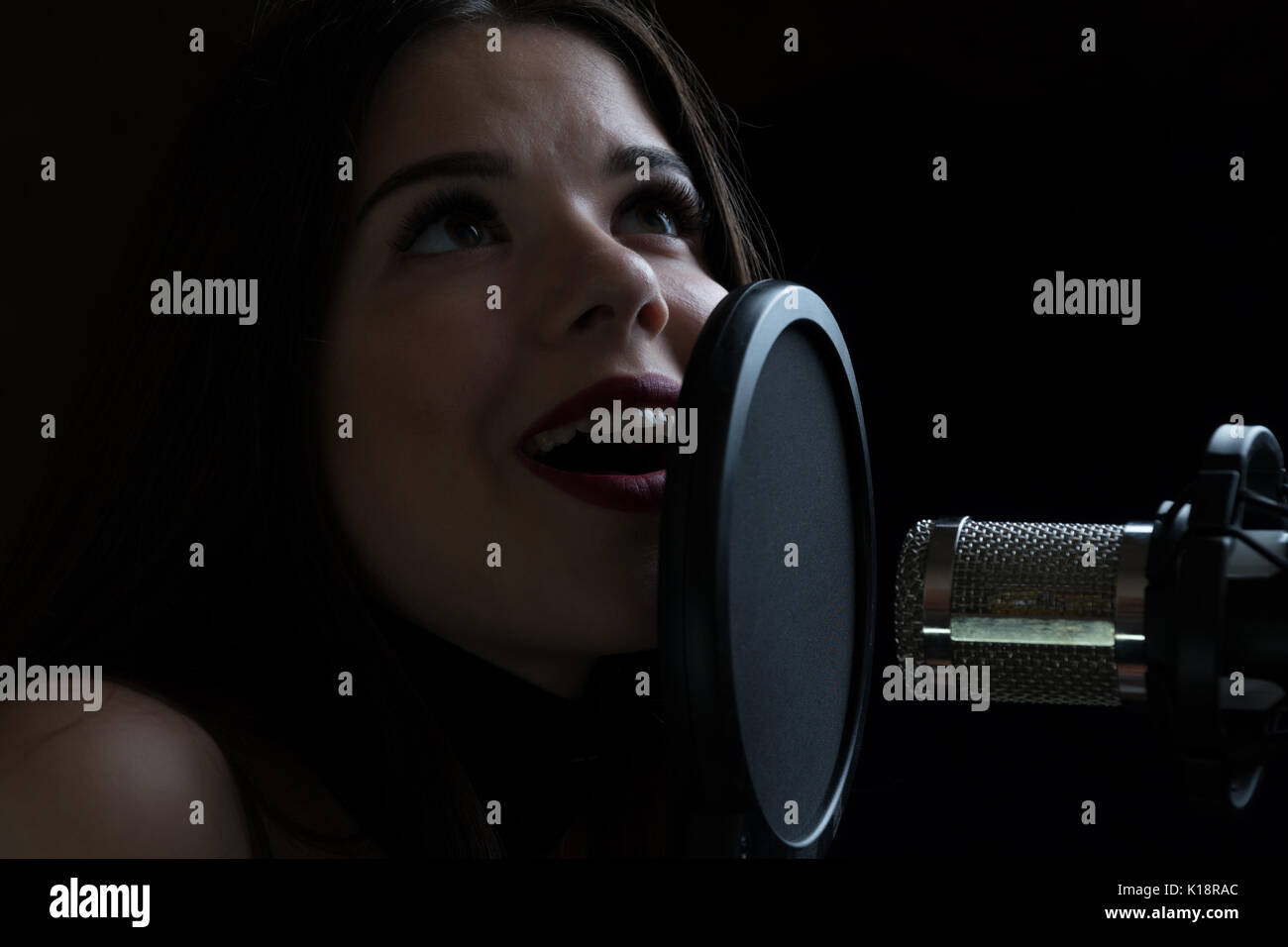 Beautiful girl singing In Recording Studio with microphone Stock Photo