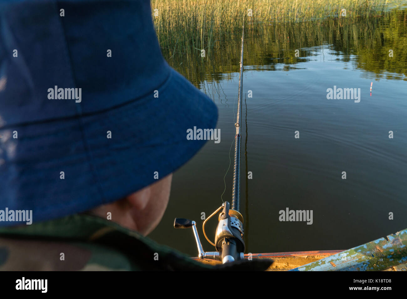 A man is fishing from a boat. View from behind the shoulder of a man ...