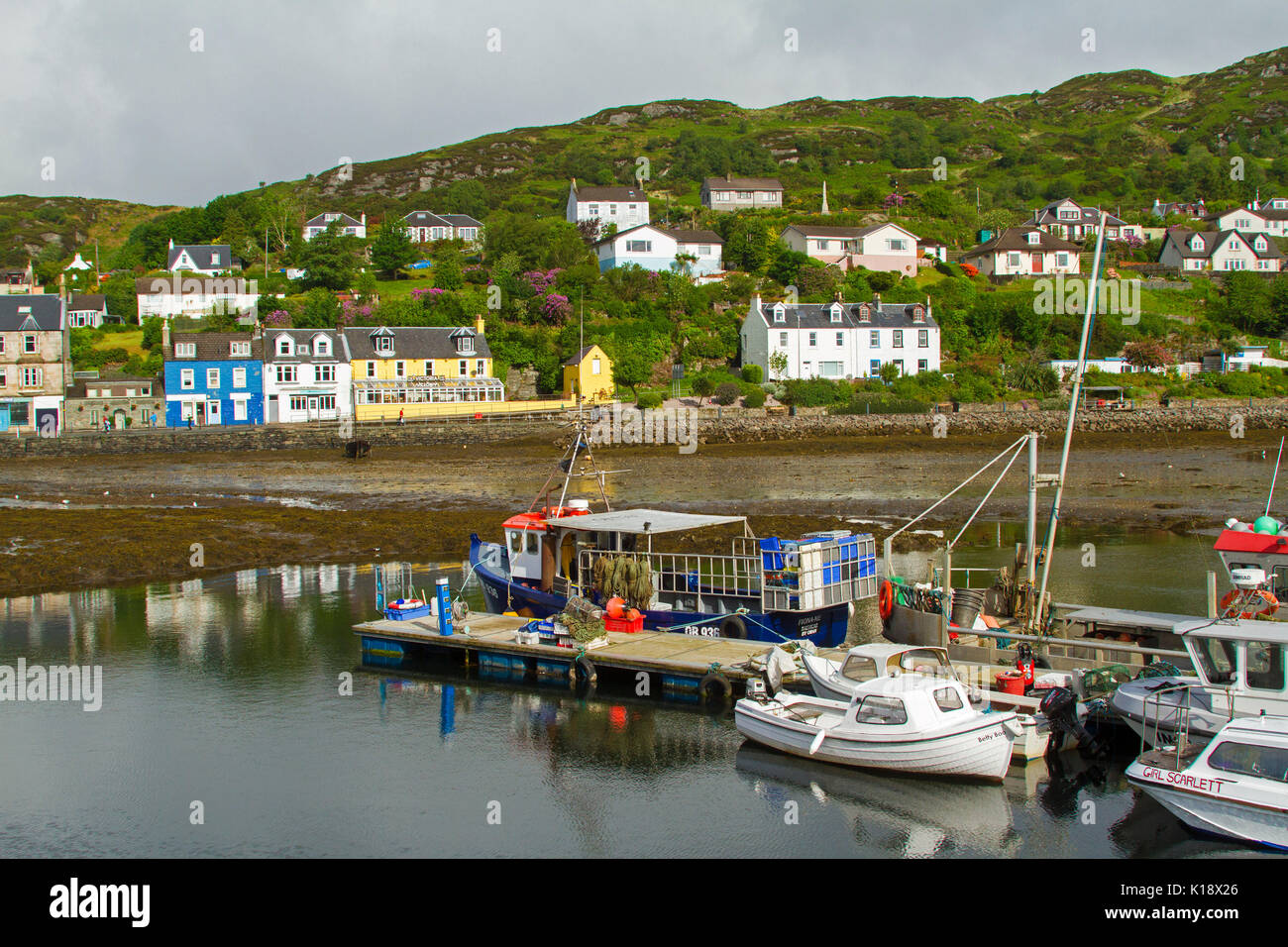 Scottish village of Tarbert with colourful buildings at foot of wooded hills and boats in harbour on Loch Tarbert, Scotland Stock Photo