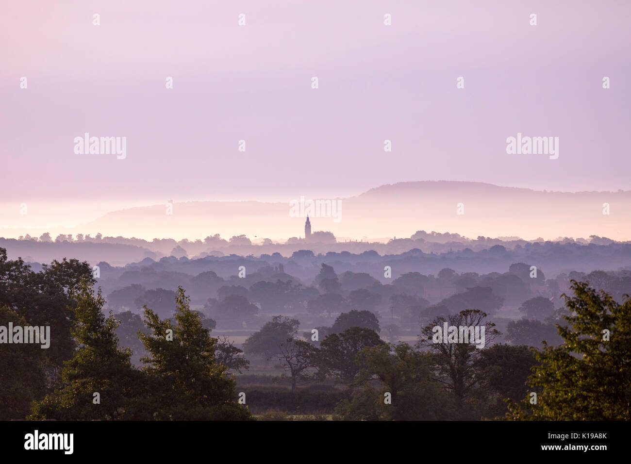 Flintshire, UK . With a warm day behind and clearing sky over Flintshire as the sun begins to break the horizon and the lighting the sky pink over the Cheshire Plain from the foothills of Flintshire Stock Photo