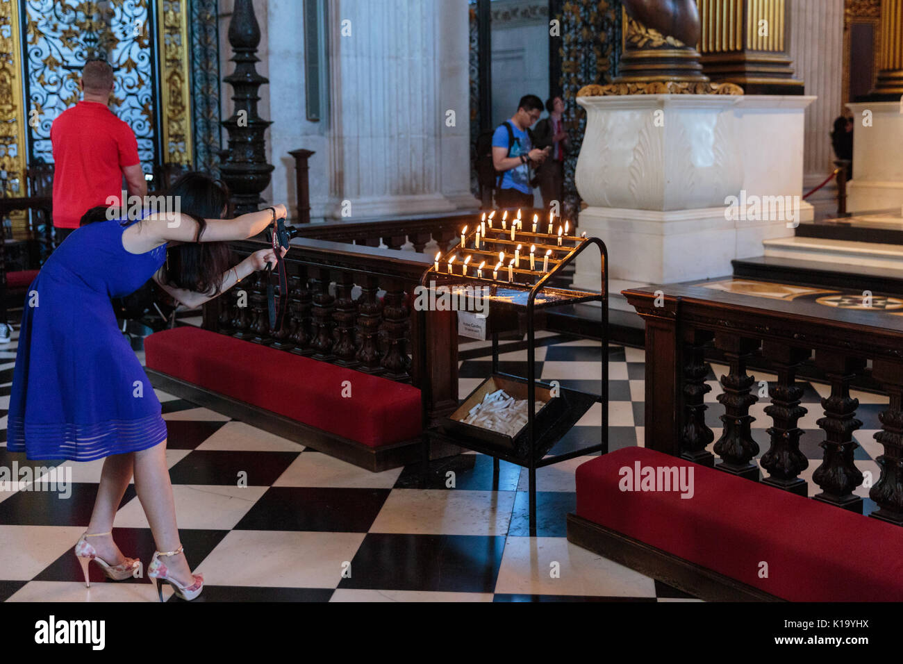 Female tourist taking photo of candles inside St Paul's Cathedral, London United Kingdom Stock Photo