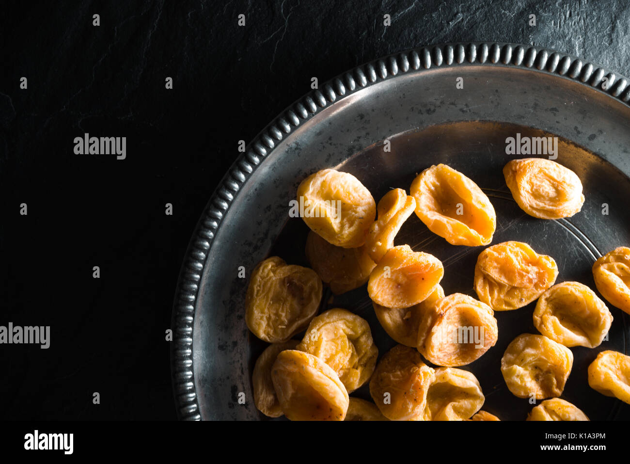 https://c8.alamy.com/comp/K1A3PM/dry-apricots-on-a-tin-plate-with-the-right-on-a-stone-table-horizontal-K1A3PM.jpg