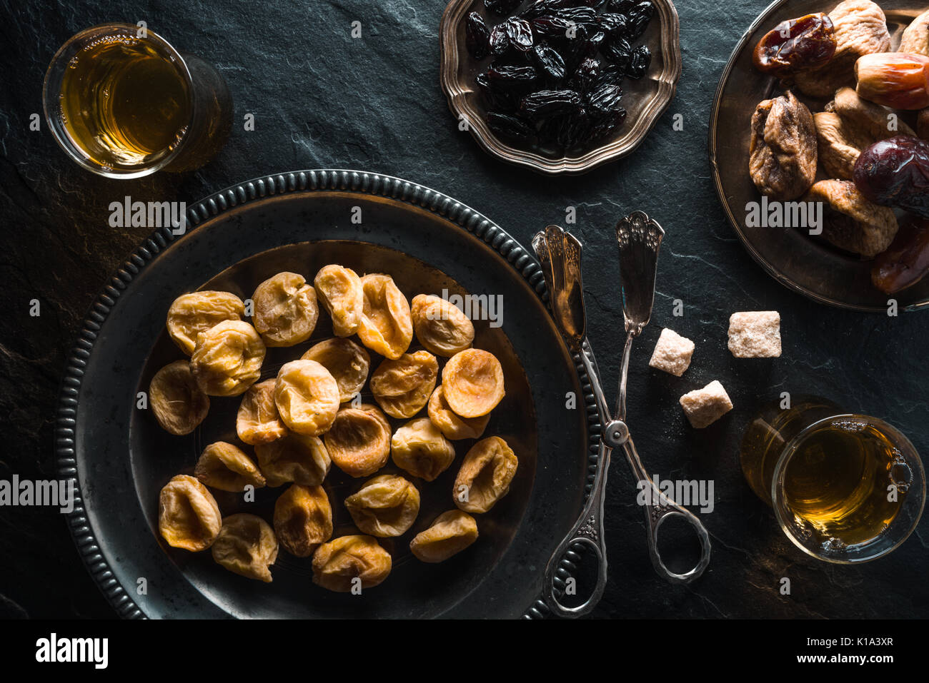 Dried apricots, dates and raisins on metal plates on a gray table horizontal Stock Photo