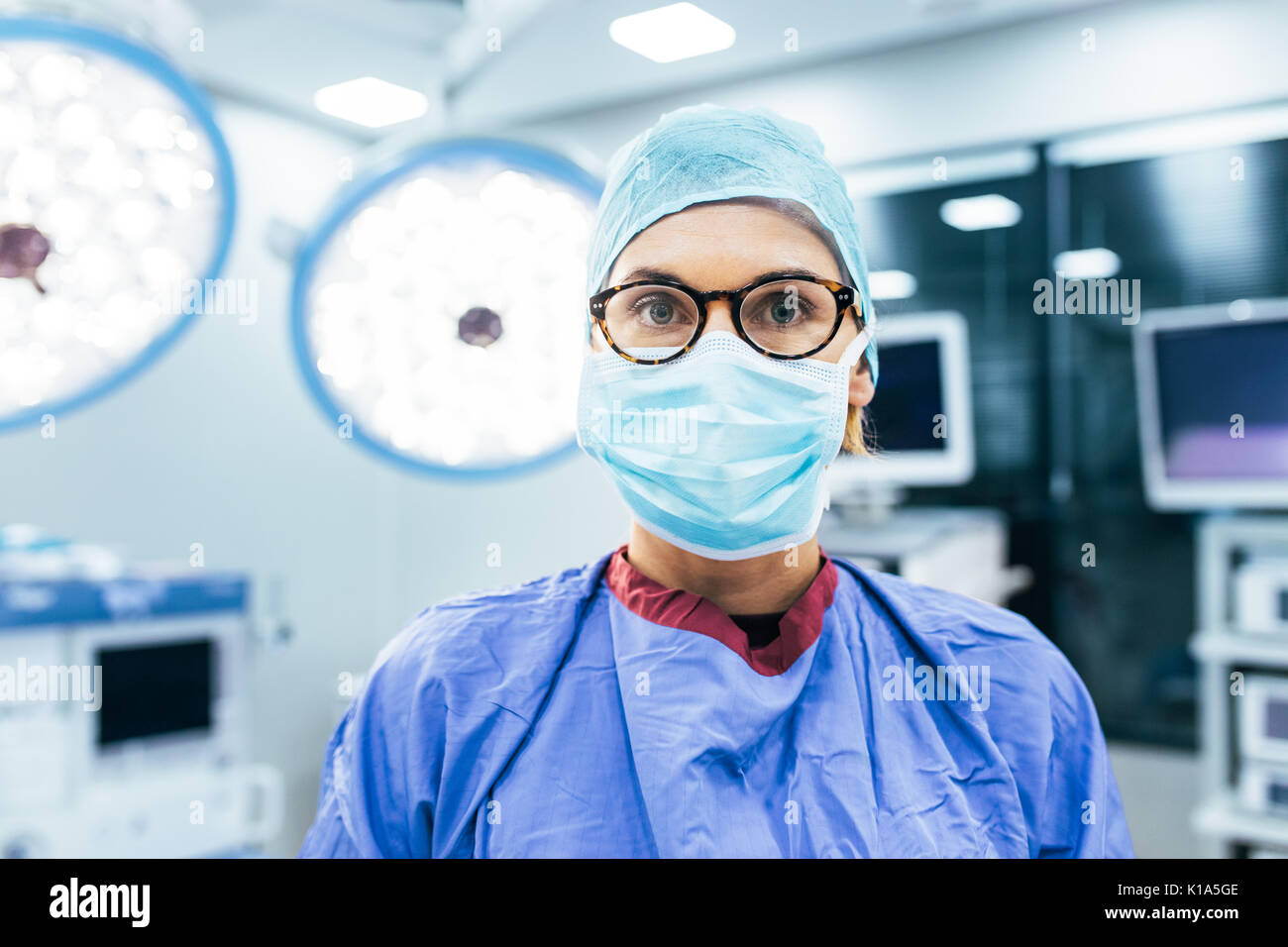 Close up portrait of female surgeon wearing surgical mask and scrubs in ...