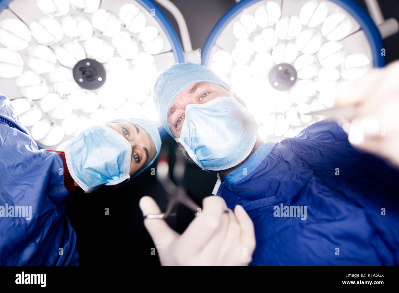 Team of surgeons operating patient under surgery lights in hospital. Doctors performing dental surgery. Stock Photo