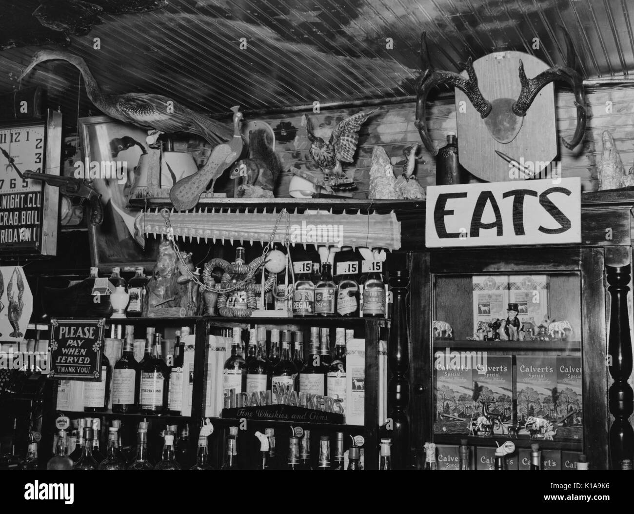 A bar interior featuring a large selection of liquor, decorated in an eclectic manner with stuffed birds, a squirrel, horns, the nose of a sawfish and a pistol, 1938. From the New York Public Library. Stock Photo