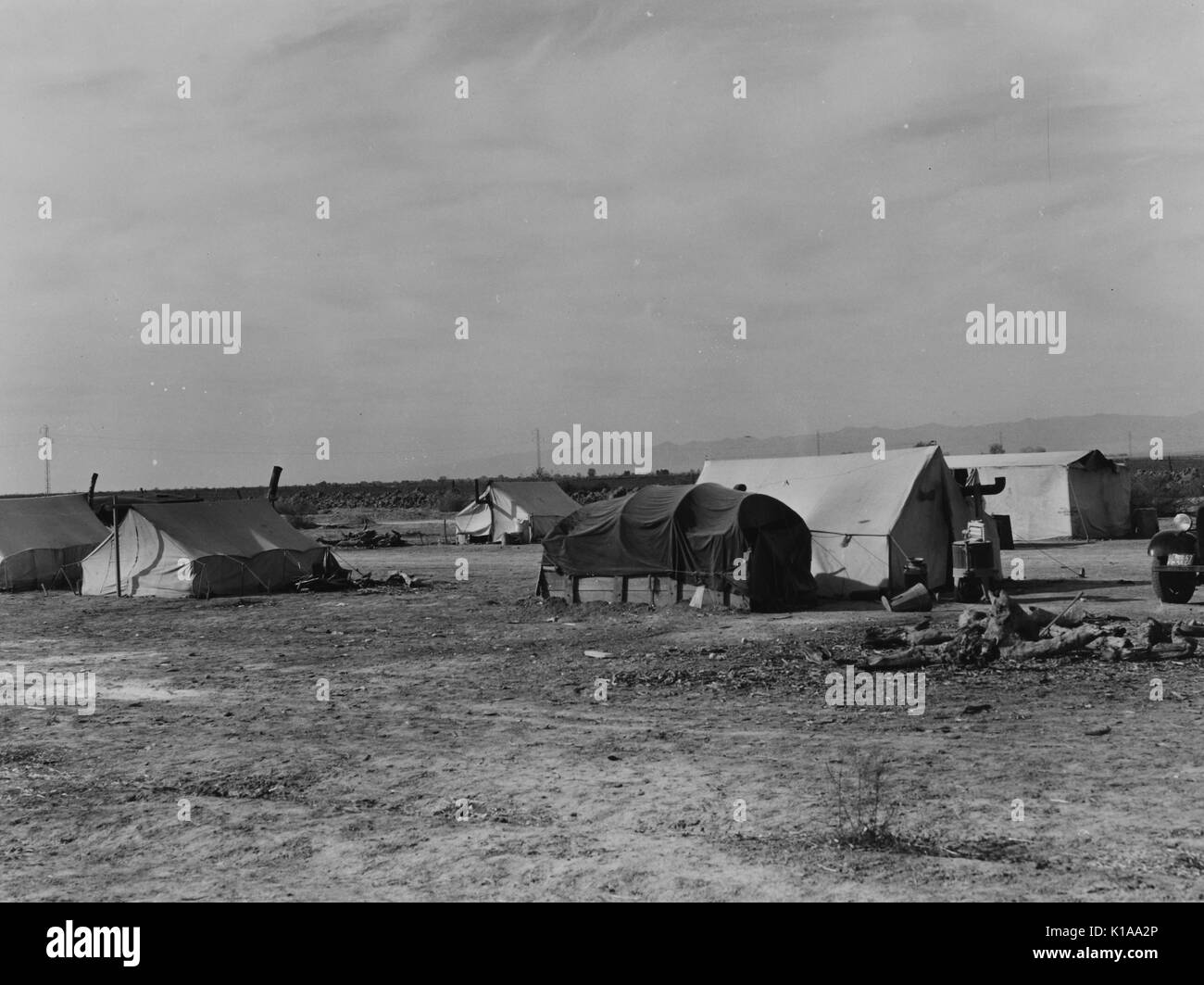 A wide angle shot of a squatters camp, the tents belong to farmers seeking work with cotton and potatoes after fleeing the drought, Kern County, California, 1937. From the New York Public Library. Stock Photo