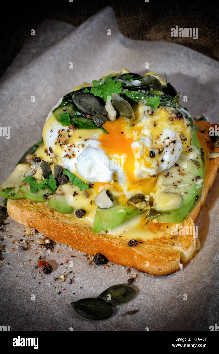 Eggs Benedict on toast with Dutch sauce, slices of avocado Stock Photo