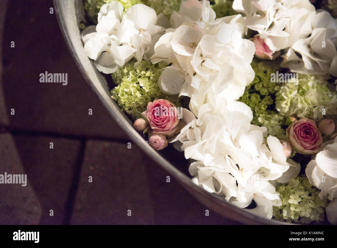 Metal tubs filled with summer flowers. Pink hydrangeas and roses and others viewed high angle on