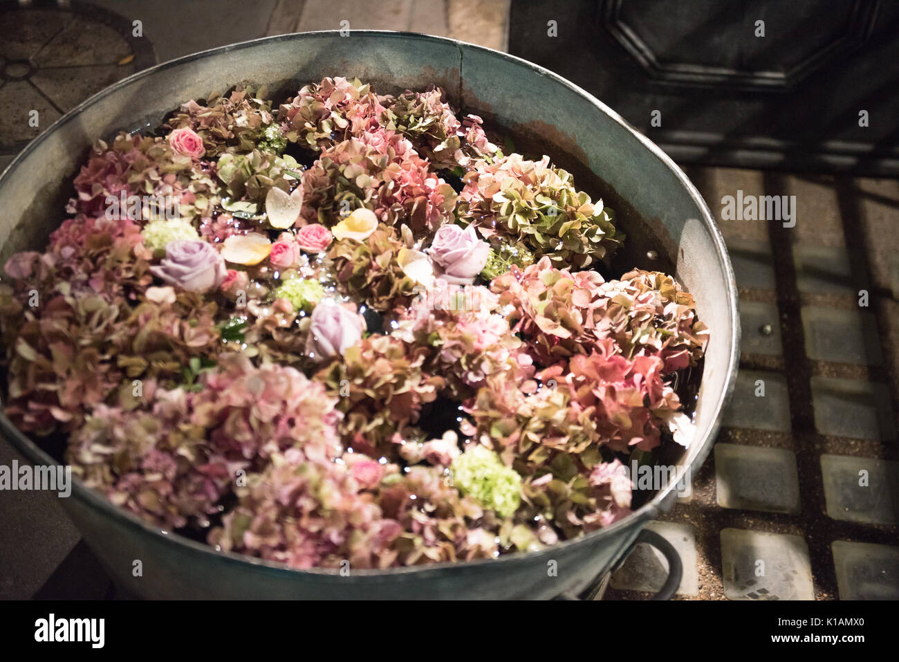 Metal tubs filled with summer flowers. Pink hydrangeas and roses and others viewed high angle on