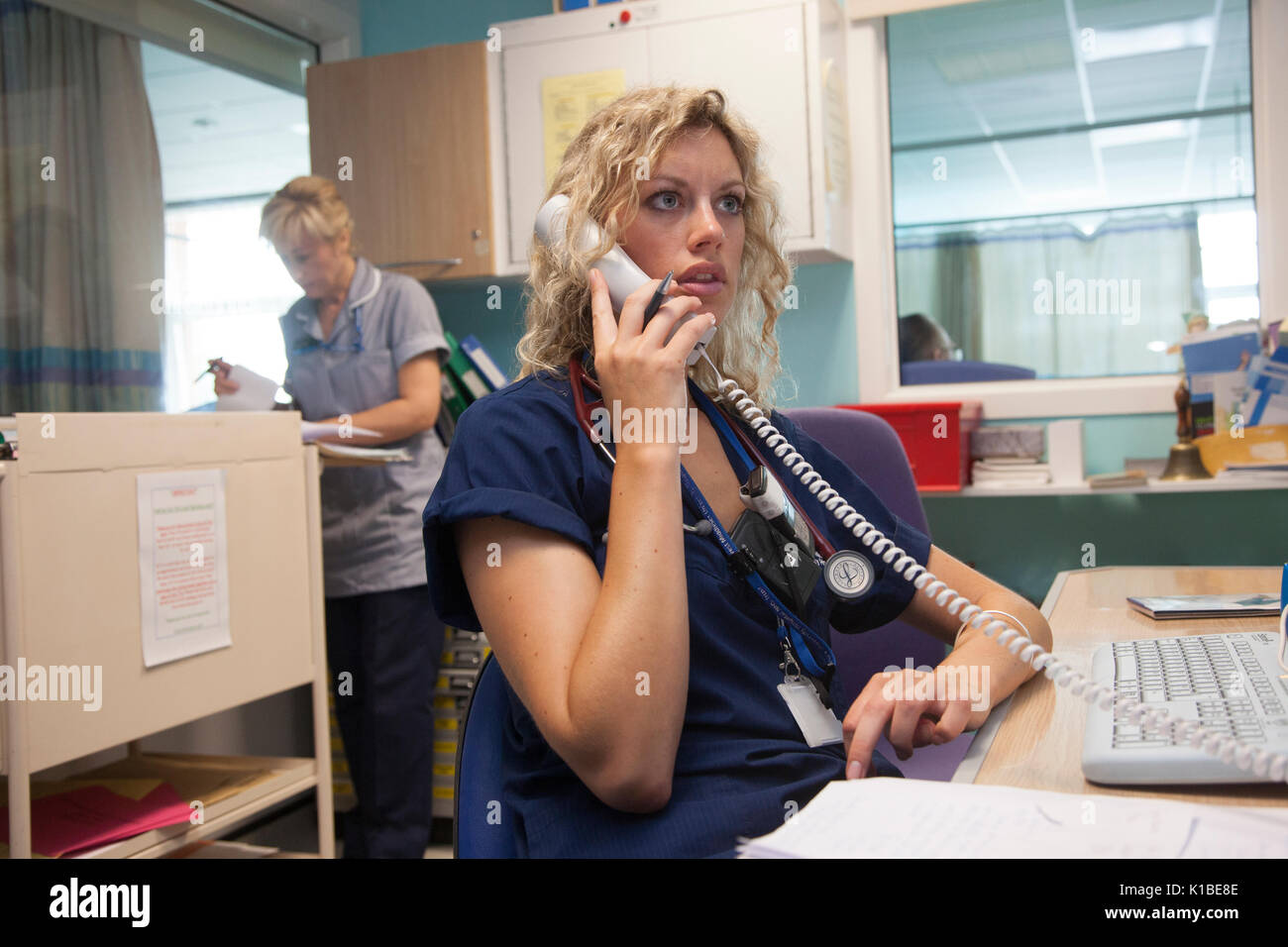 A doctor takes a call on a busy ward in an NHS Hospital Stock Photo