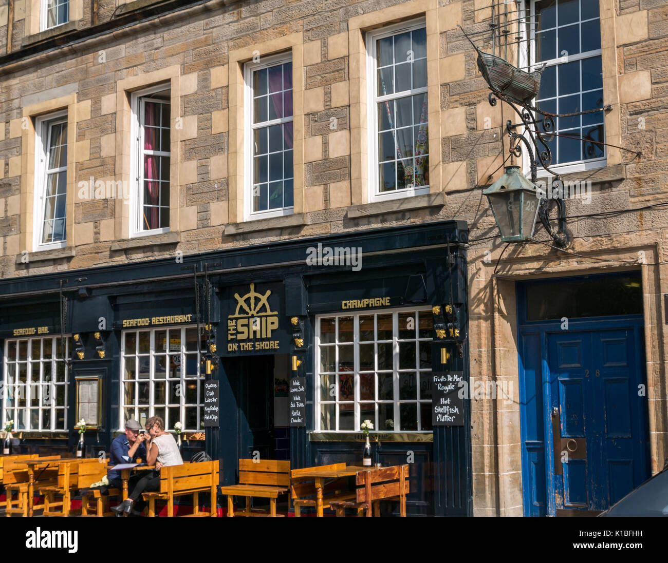 Leith restaurant, The Ship on the Shore, with Persevere ship model emblem on wall and couple sitting outside in sun, Edinburgh, Scotland, UK Stock Photo