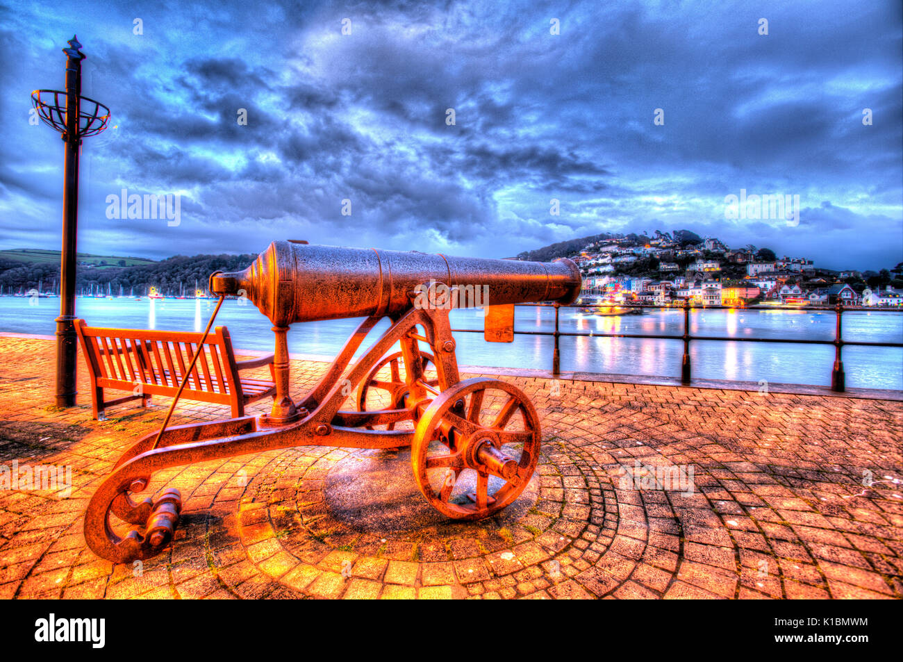 Town of Dartmouth, England. An antique cannon on Dartmouth’s promenade with the River Dart and Kingswear in the background. Stock Photo