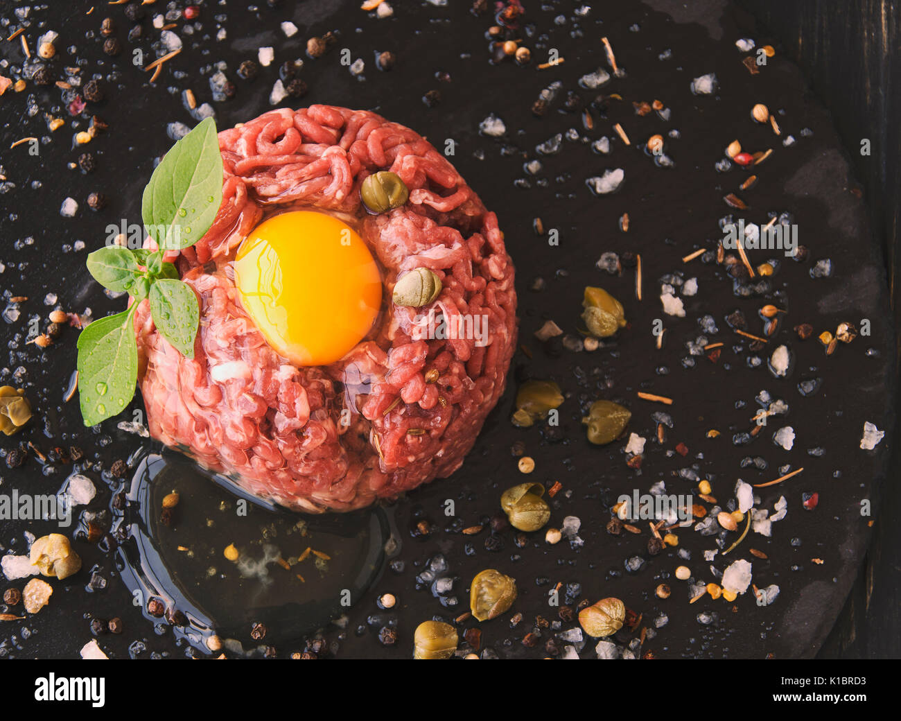 Steak tartare of raw minced meat with salt and spices, on a black ...