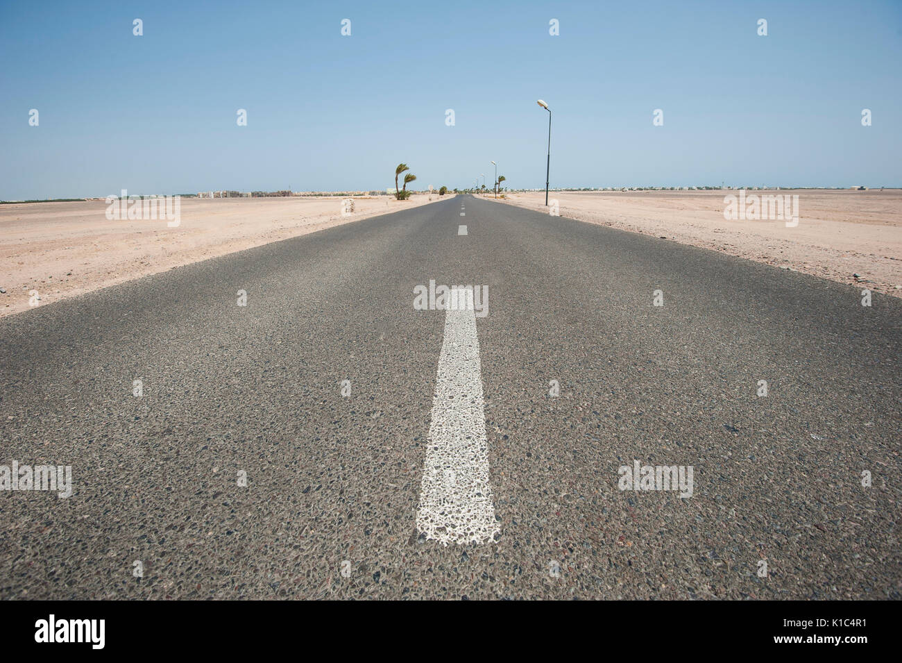 Long straight desert road in remote arid landscape going to infinity vanishing point Stock Photo