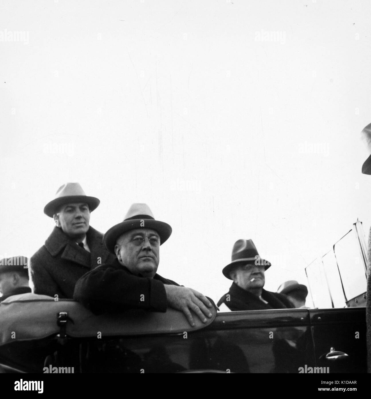 President Franklin Roosevelt, Doctor Rexford Tugwell, and a mature man, all in a car, with hats, facing the camera, Greenbelt, Maryland, 1936. From the New York Public Library. Stock Photo