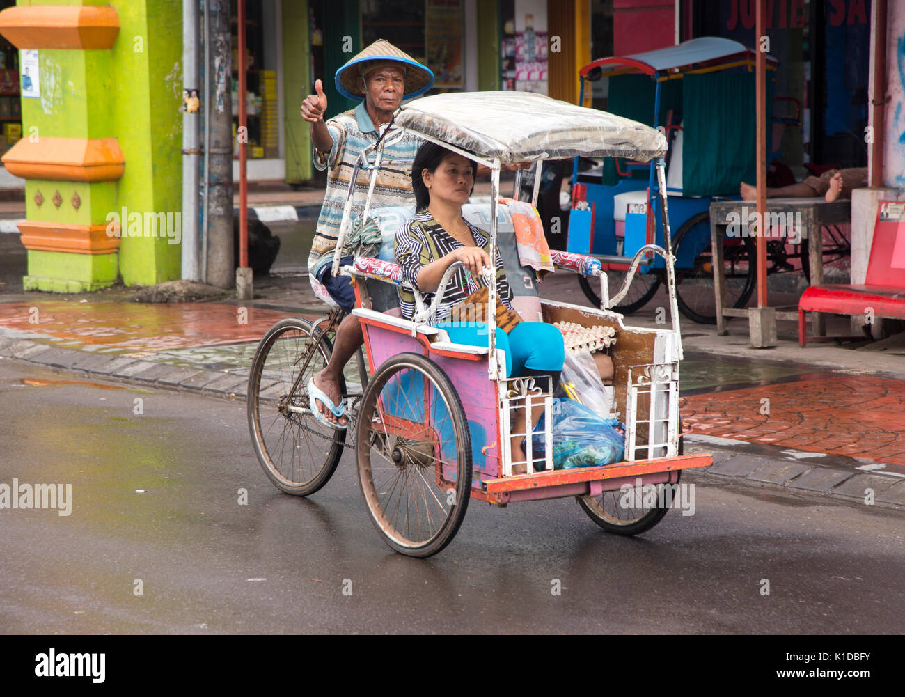 Cyclo driver with a passenger in Makassar, Indonesia Stock Photo