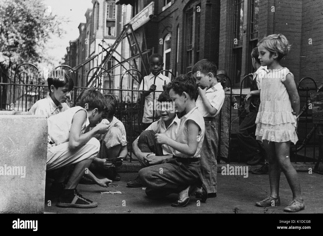 Children playing cards in front yard in slum area near Union Station, a section of town inhabited by both Caucasian and African-American residents, Washington, DC, 1935. From the New York Public Library. Stock Photo