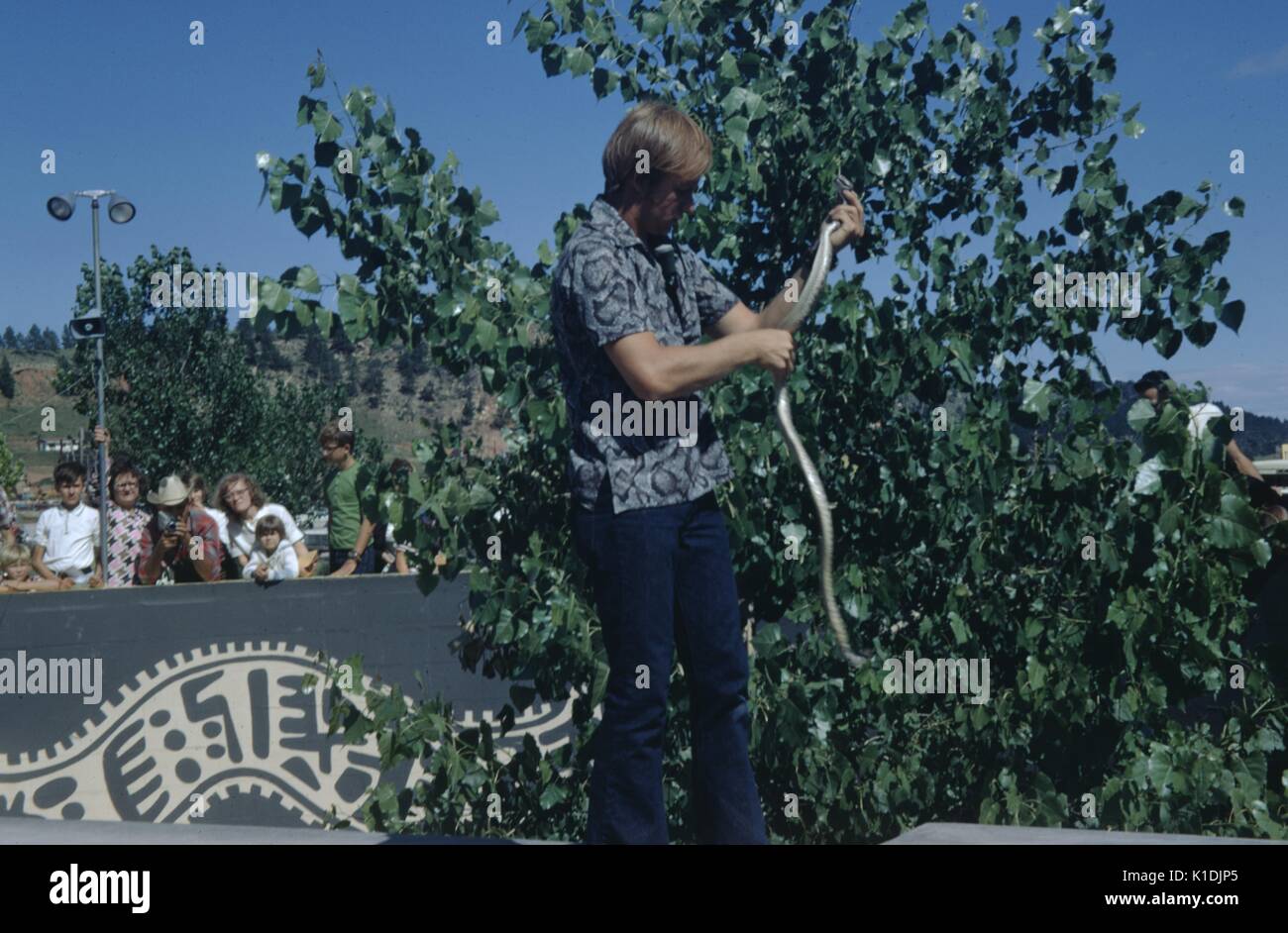 Performer Holding A Snake With A Crowd Looking On At The Reptile