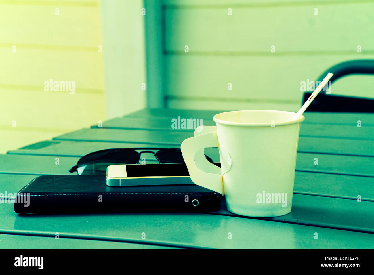 Mobile phone with paper cup of coffee on table Stock Photo
