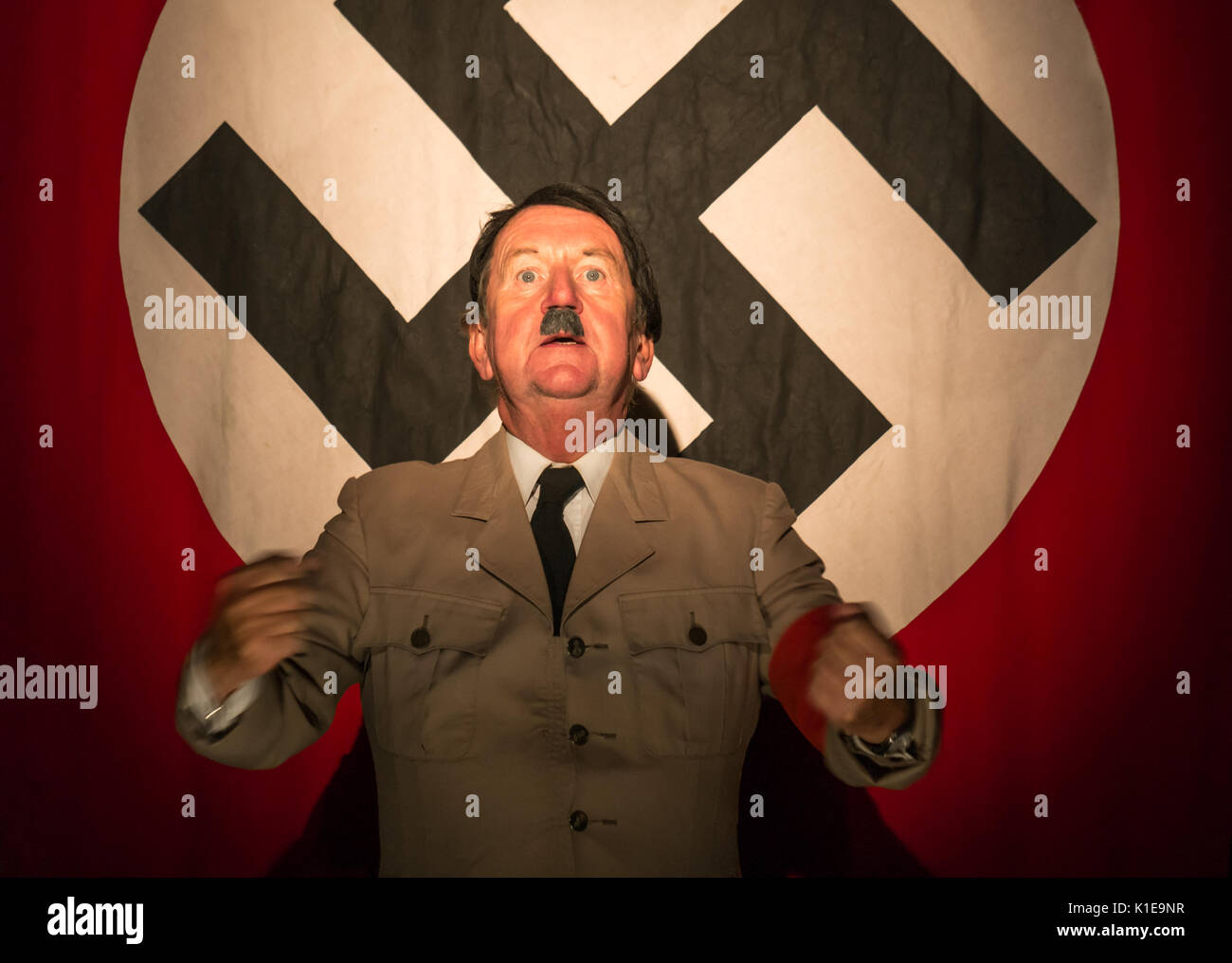 Pleasance Courtyard, Edinburgh, Scotland, United Kingdom, 26th August 2017. Pip Utton, versatile actor and Fringe Festival regular, in one man solo role of historical figure Adolf Hitler at Edinburgh Fringe Festival, Pleasance Courtyard, standing in front of a large banner with a swastika Stock Photo