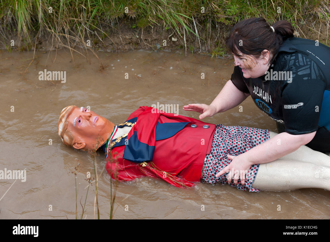 Llanwrtyd Wells, Powys, UK. 27th August, 2017. Bog Snorkelling aficionado Julia Galvin rescues an effigy of Donald Trump in new novelty event which has been added this year - Save Trump from the Bog.The 32nd annual World Bog Snorkelling Championships, conceived over 30 years ago in a Welsh pub by landlord Gordon Green, are held at the Waen Rhydd Bog. Using unconventional swimming strokes, participants swim two lengths of a 55 metre trench cut through a peat bog wearing snorkel mask and flippers. Credit:  Graham M. Lawrence/Alamy Live News Stock Photo