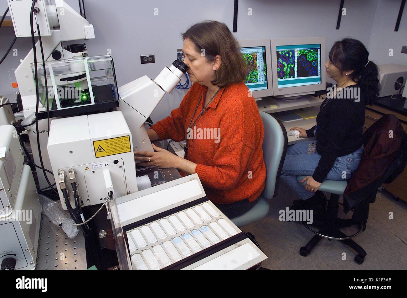CDC scientists at work using a confocal microscope. LabScience, Using laser light, CDC laboratory scientists sometimes work with a confocal microscope when diagnosing various pathogens. Image courtesy CDC, 2002. Stock Photo