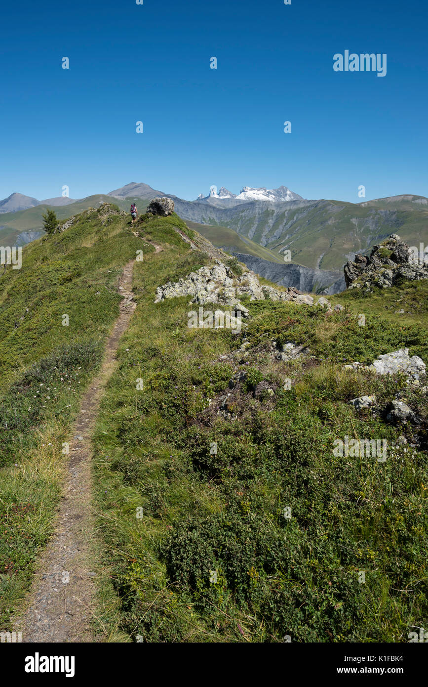 Girl trekking on a trail in the French Alps landscape with snowy peaks ...