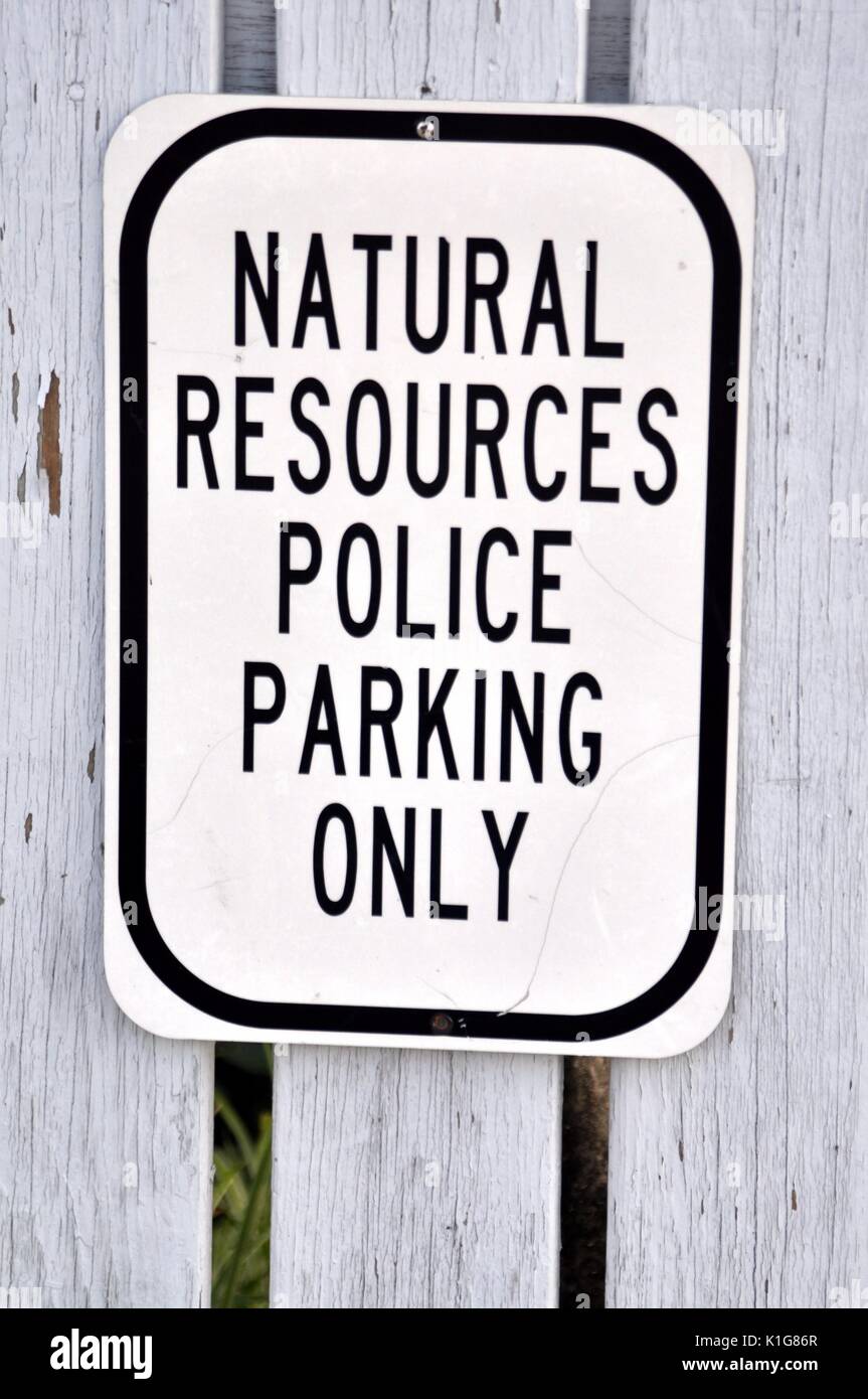 Black and White Natural Resources Police Parking Only sign against a grey fence. Stock Photo