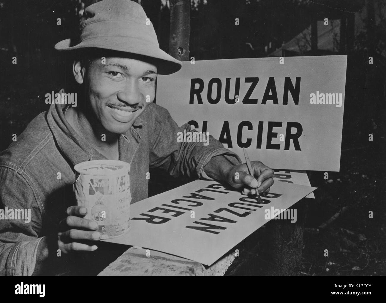 African-American soldier painting a sign that reads Rouzan Glacier, as part of the ALCAN highway project, 1942. From the New York Public Library. Stock Photo