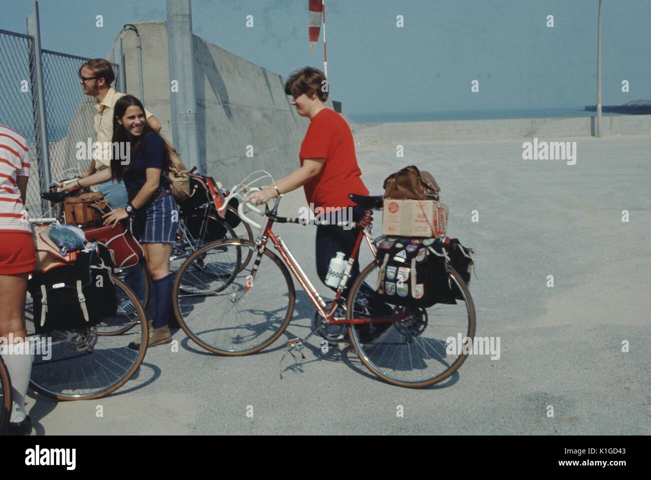 Two girls with their bike talking as they stop by a fenced area, with two other people standing by, 1966. Stock Photo