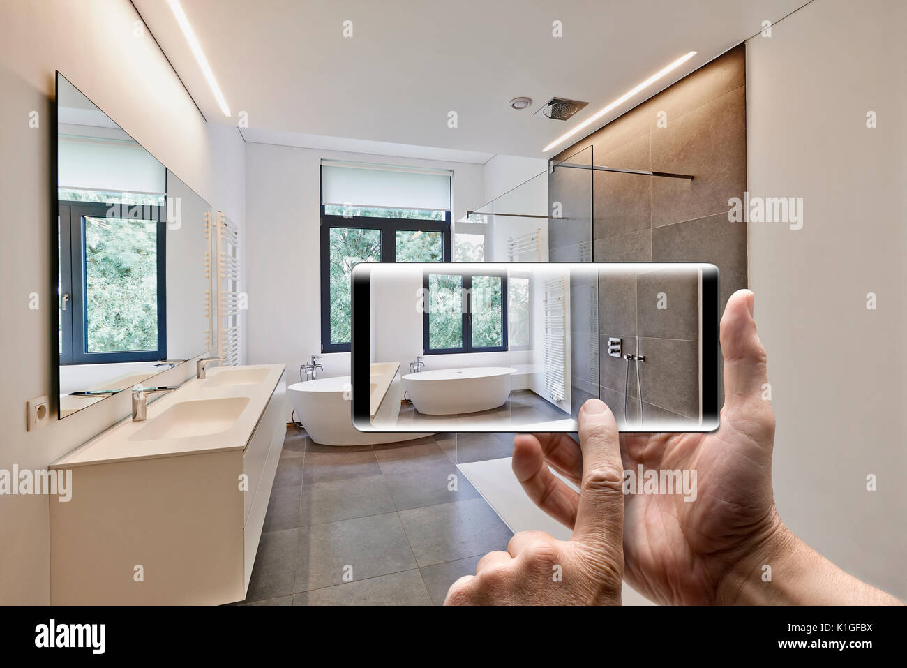 Mobile device with man hands taking picture in  tiled bathroom with windows towards garden Stock Photo