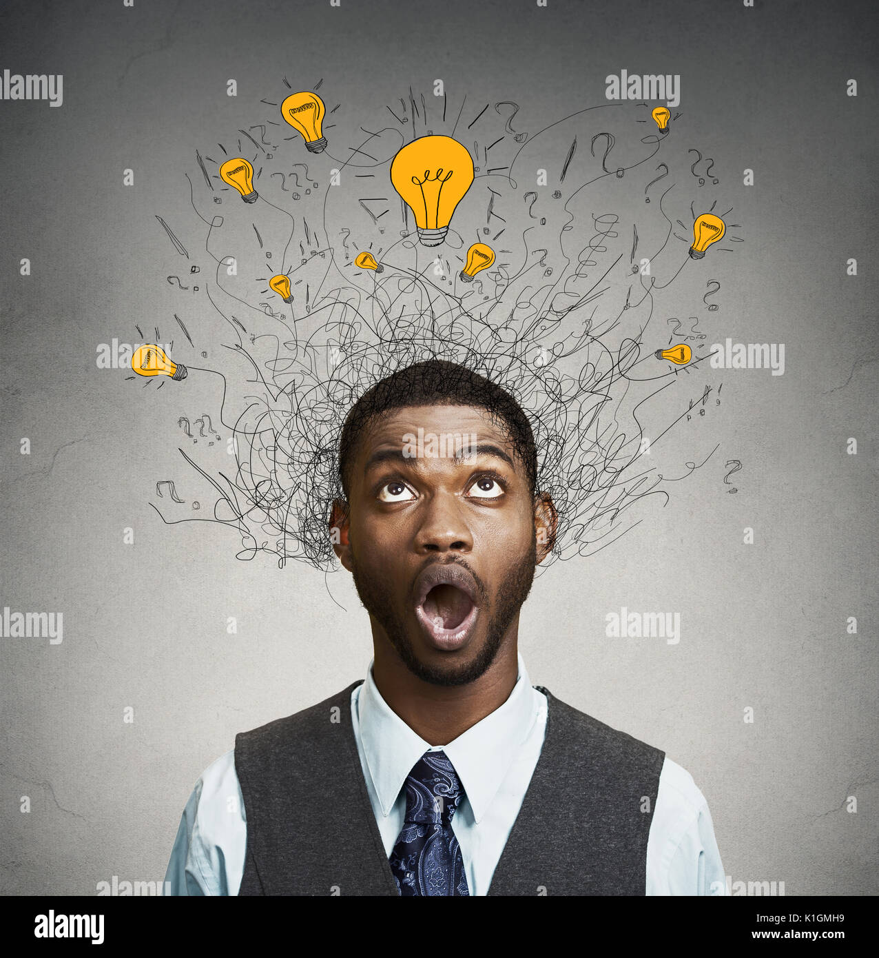 Young man with many idea light bulbs above head looking up isolated on gray wall background. Stock Photo