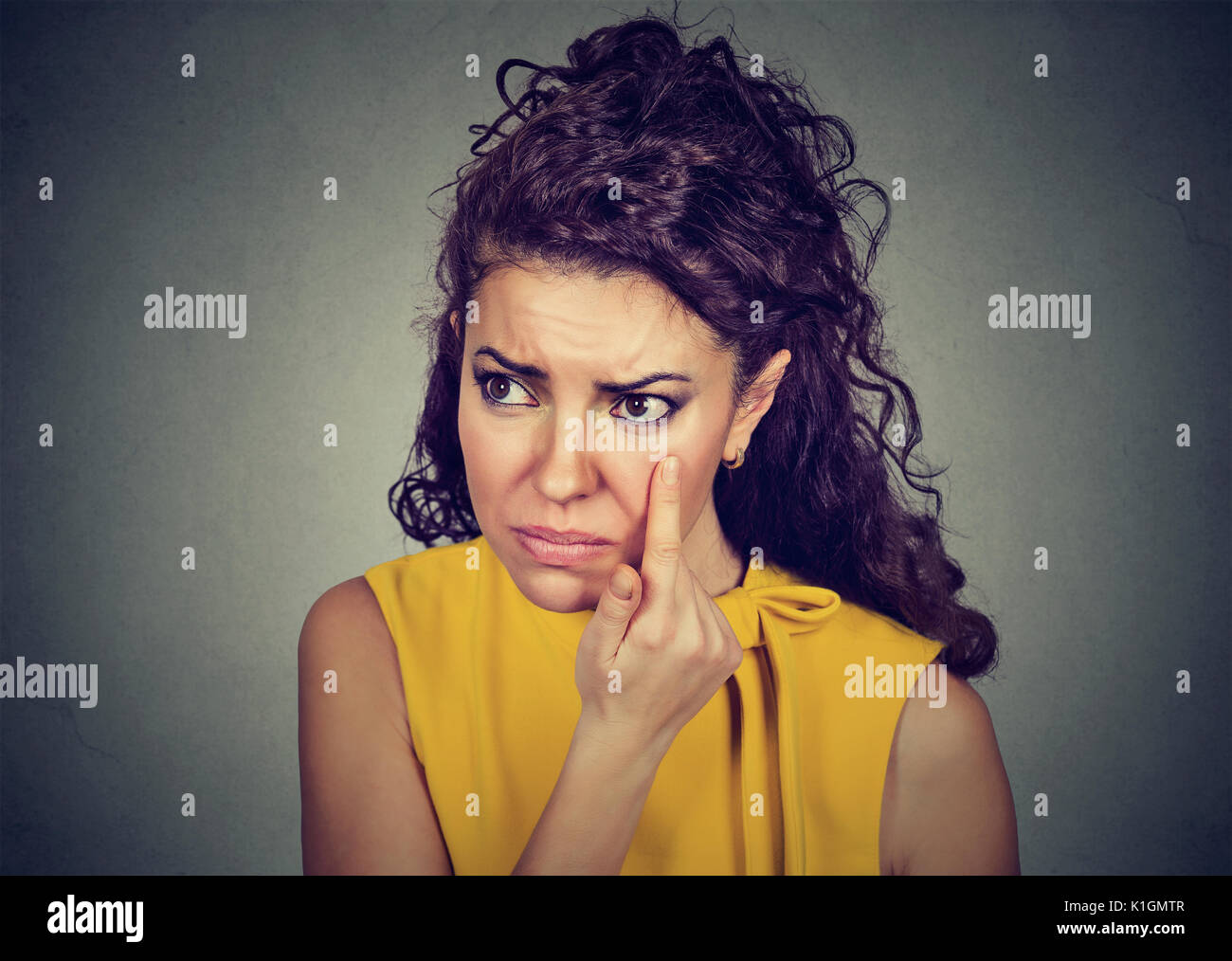 woman pulling down eyelid checking her eye looking in morrow feels unwell has black circles Stock Photo