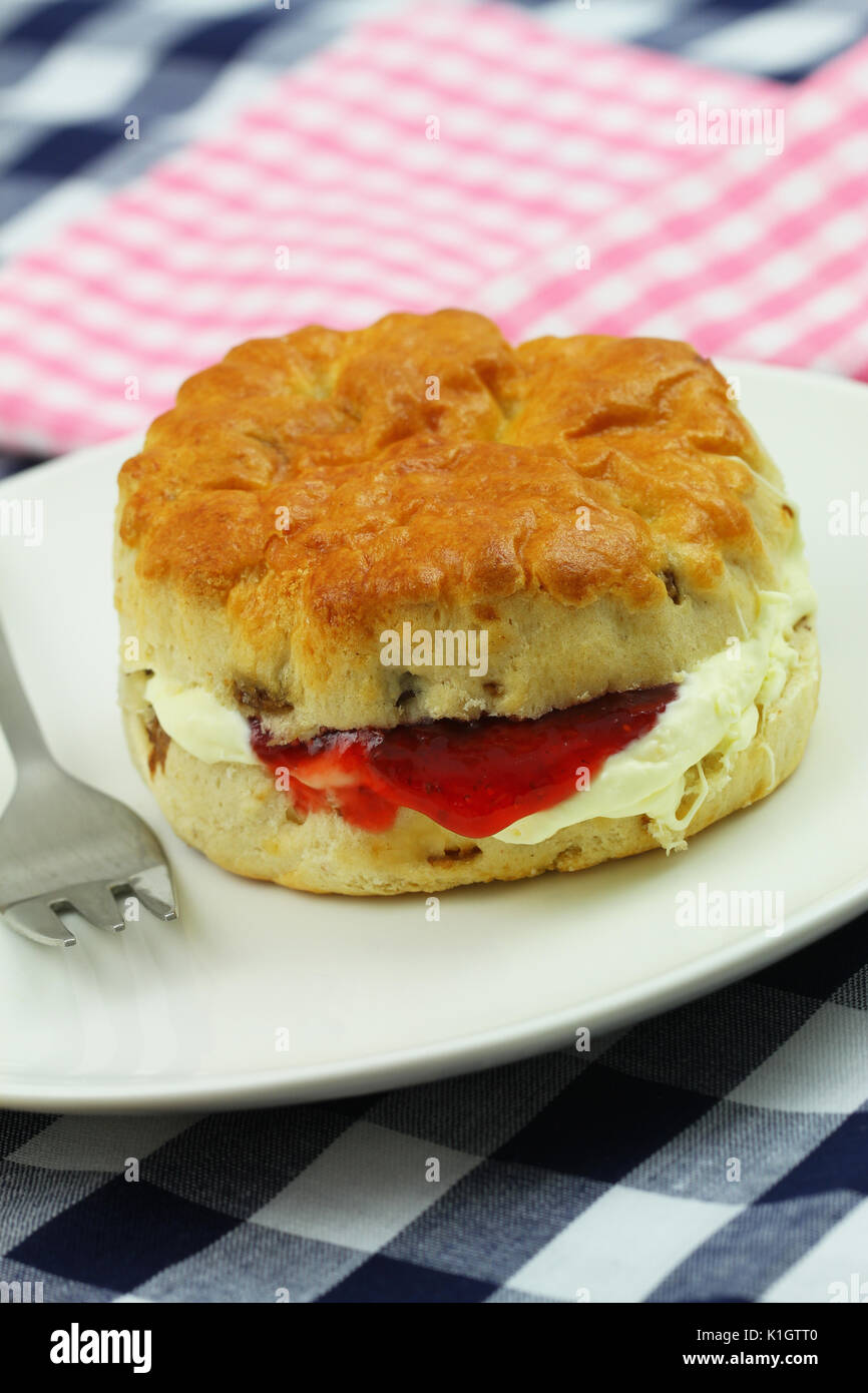 Traditional English scone with strawberry jam and fresh clotted cream on white plate, closeup Stock Photo