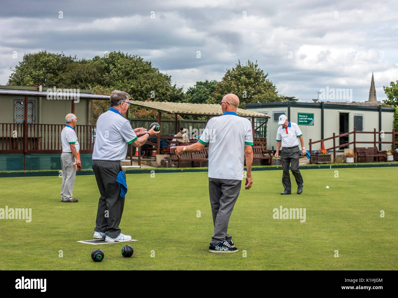 Elderly / old / senior men playing a traditional game of bowls on a flat bowling green at a village club. Langtoft, Lincolnshire, England, UK. Stock Photo