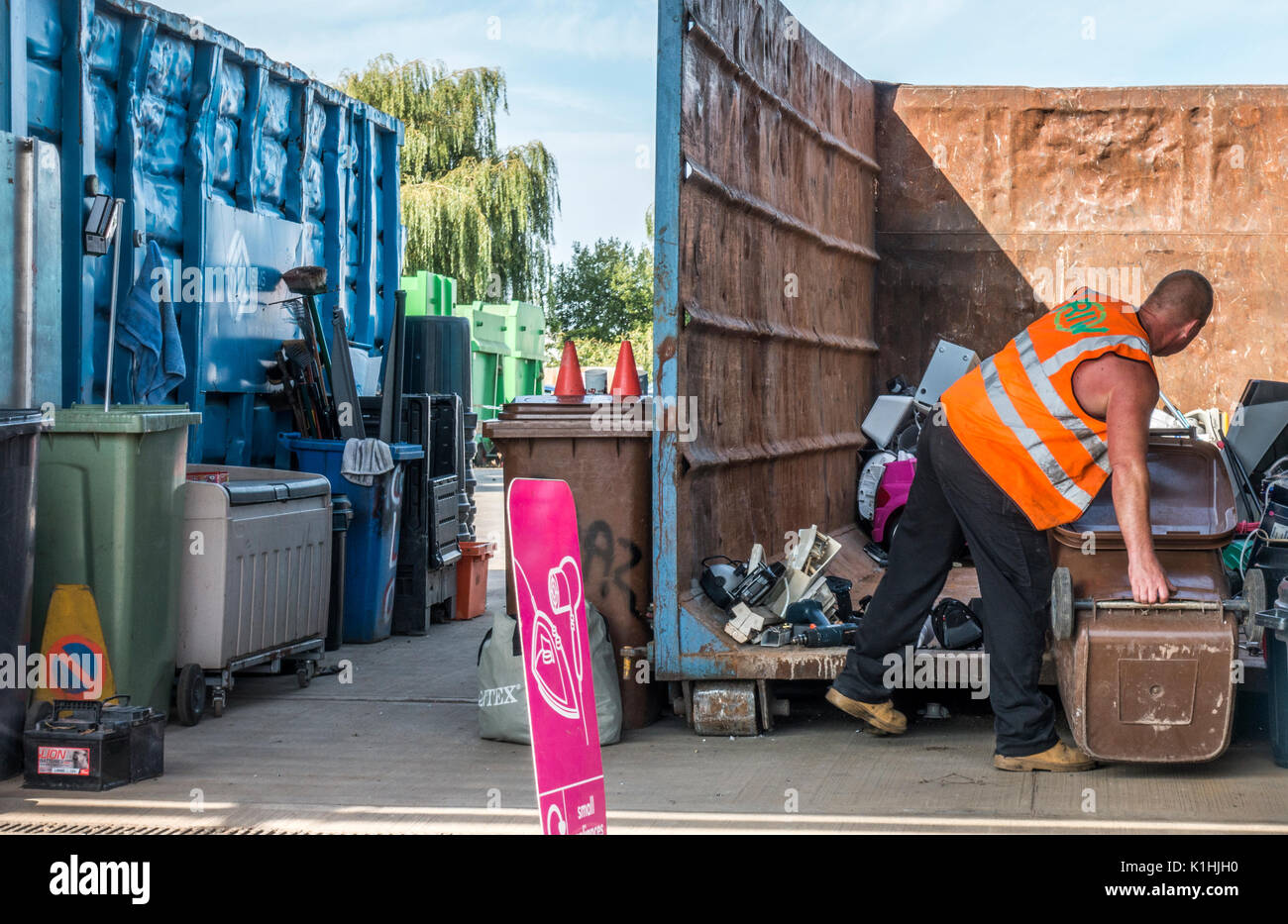 A male employee about to empty a wheely bin at a council / municipal recycling centre / refuse tip in Bourne, Lincolnshire, England, UK. Stock Photo