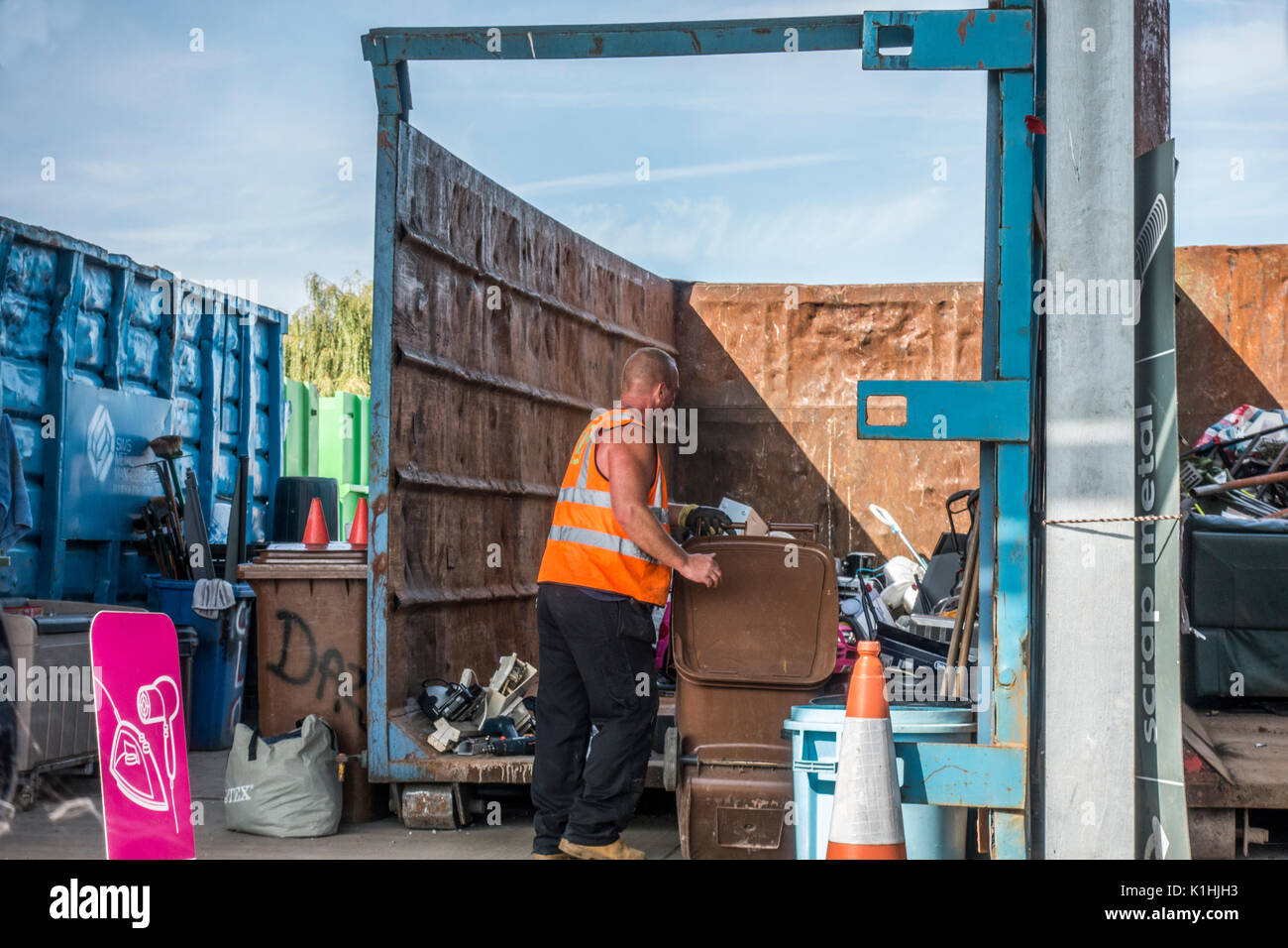 A male employee emptying a wheely bin at a council / municipal recycling centre / refuse tip in Bourne, Lincolnshire, England, UK. Stock Photo