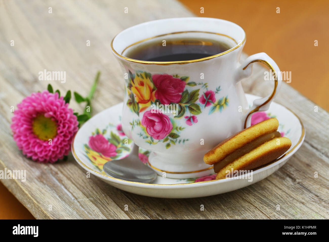 Cup of black tea in vintage porcelain cup with Japanese cookie and daisy flower Stock Photo