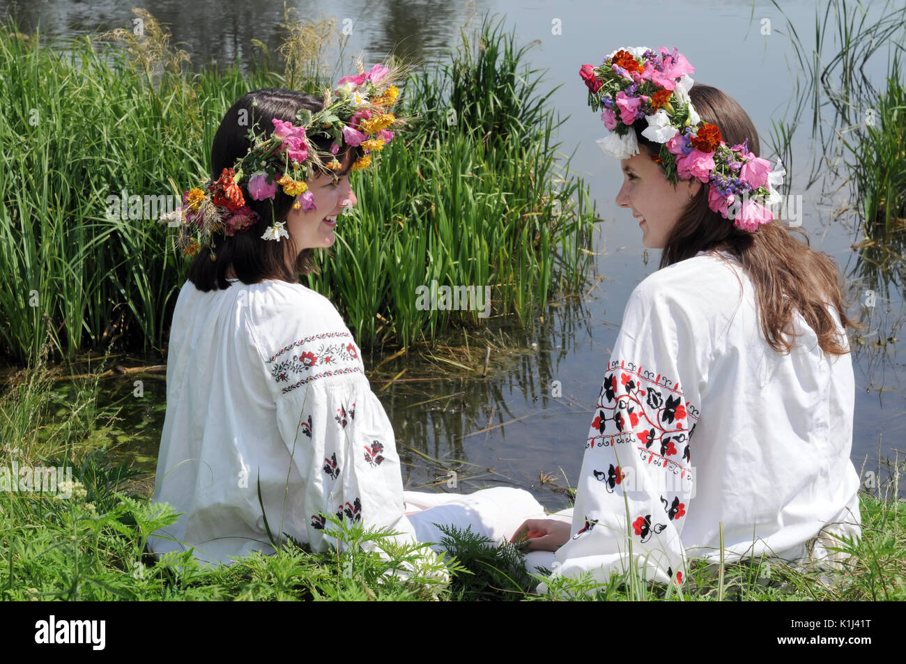 two ukrainian teenage girls in traditional clothes against  rural landscape background Stock Photo