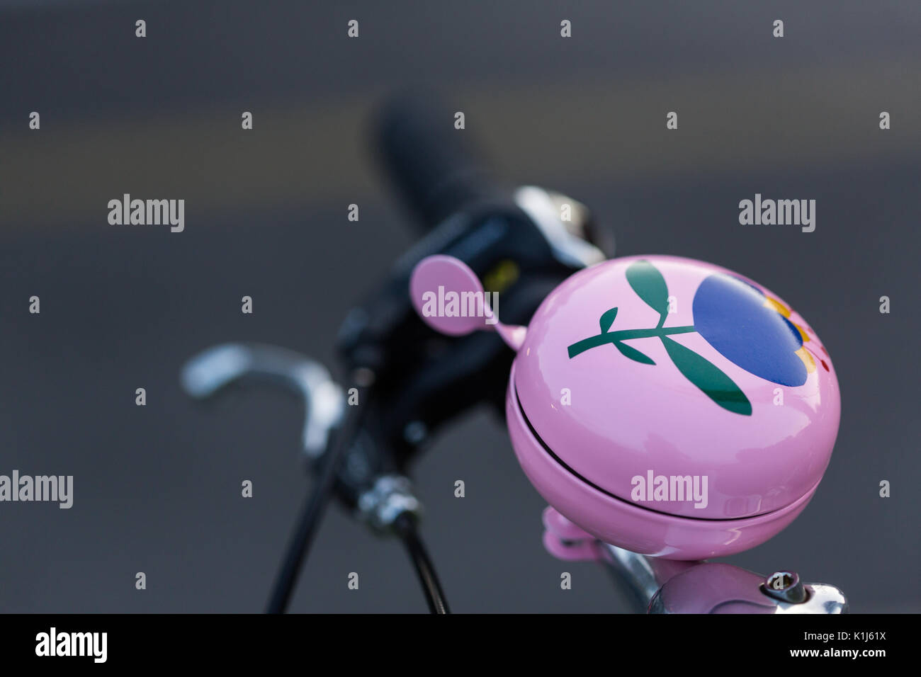A bicycle bell pink with the design of a flower on his handlebars. This