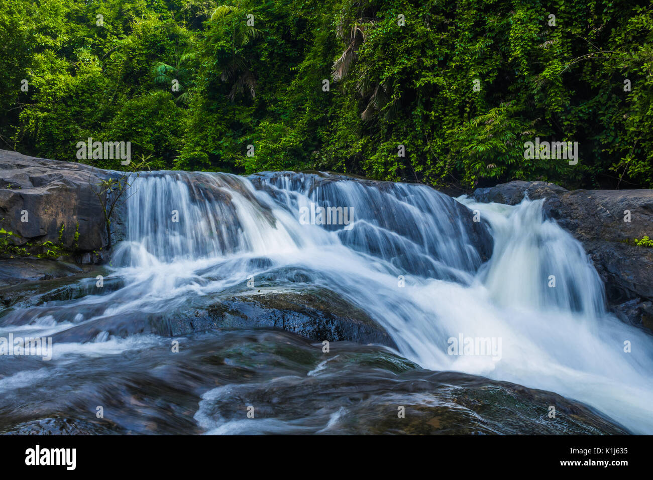 Waters of the Tambdi Surla Waterfall running through the rocks. Stock Photo