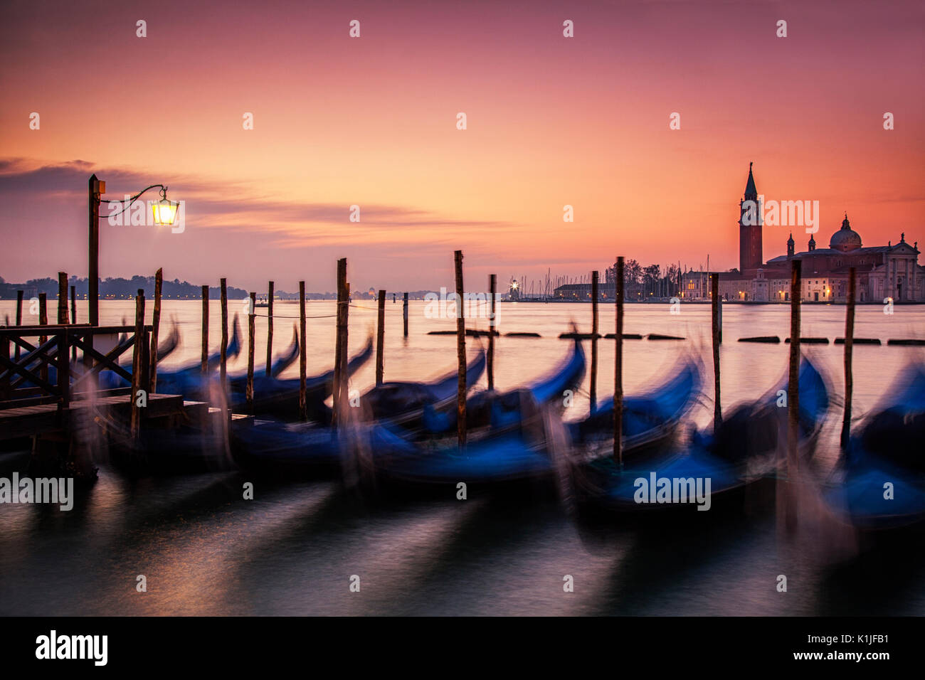 Sinrise over the gondolas of Venice, Italy and the island off San Giorgio Maggiore. Stock Photo