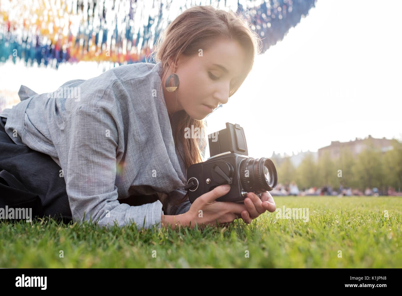 Pretty caucasian female using film photocamera. Traveling woman taking photo on vintage camera outdoor in summer Stock Photo