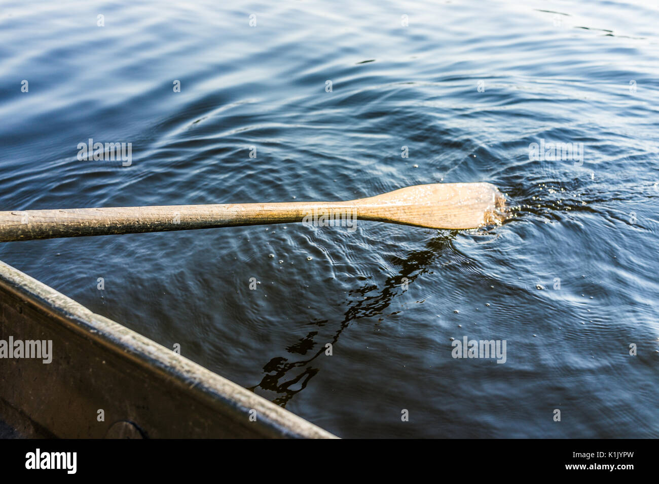 Closeup of oar paddle from row boat moving in water on green lake with  ripples Stock Photo - Alamy